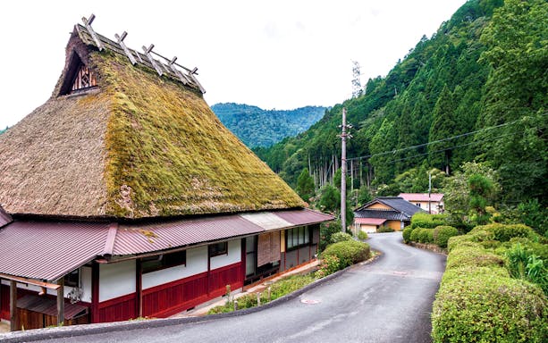 Traditional thatched-roof house in Miyama Kayabuki No Sato, surrounded by lush greenery, Kyoto Day Tour.