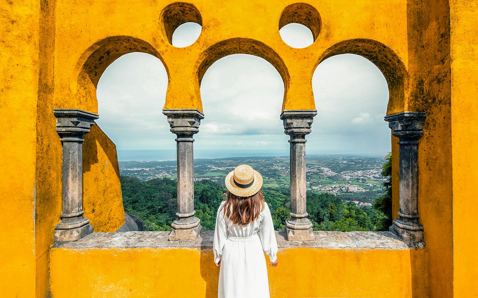 Person viewing landscape through arches at Pena Palace, Sintra, Portugal.