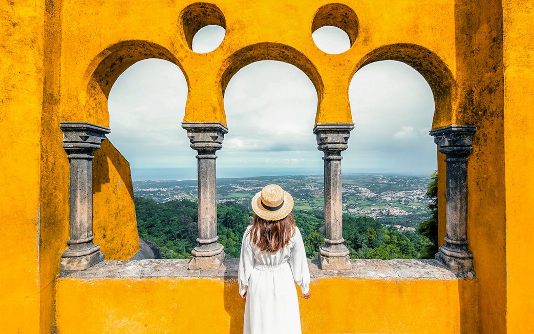 Person viewing landscape through arches at Pena Palace, Sintra, Portugal.