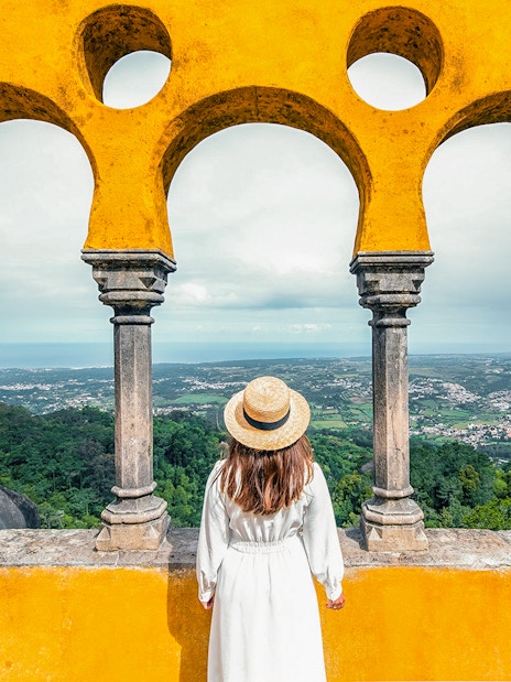 Person viewing landscape through arches at Pena Palace, Sintra, Portugal.