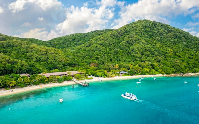 Boats near the shore of Fitzroy Island with lush green hills in the background.