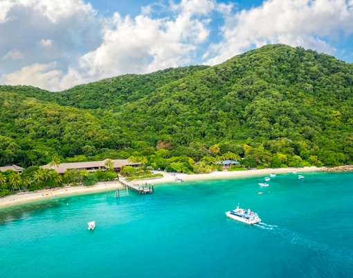Boats near the shore of Fitzroy Island with lush green hills in the background.