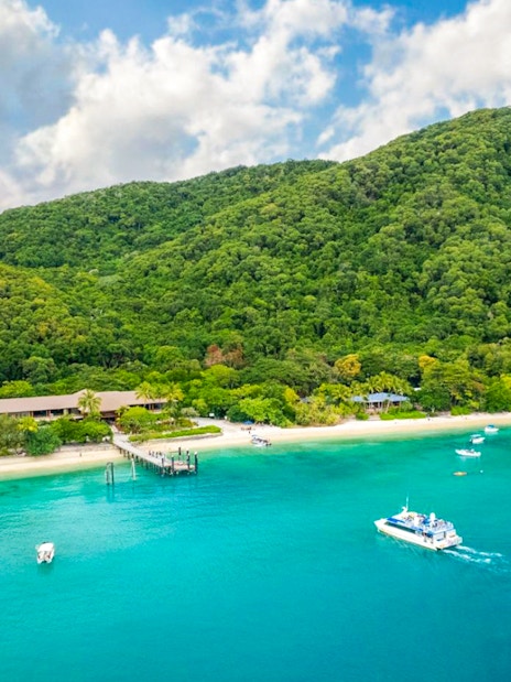 Boats near the shore of Fitzroy Island with lush green hills in the background.