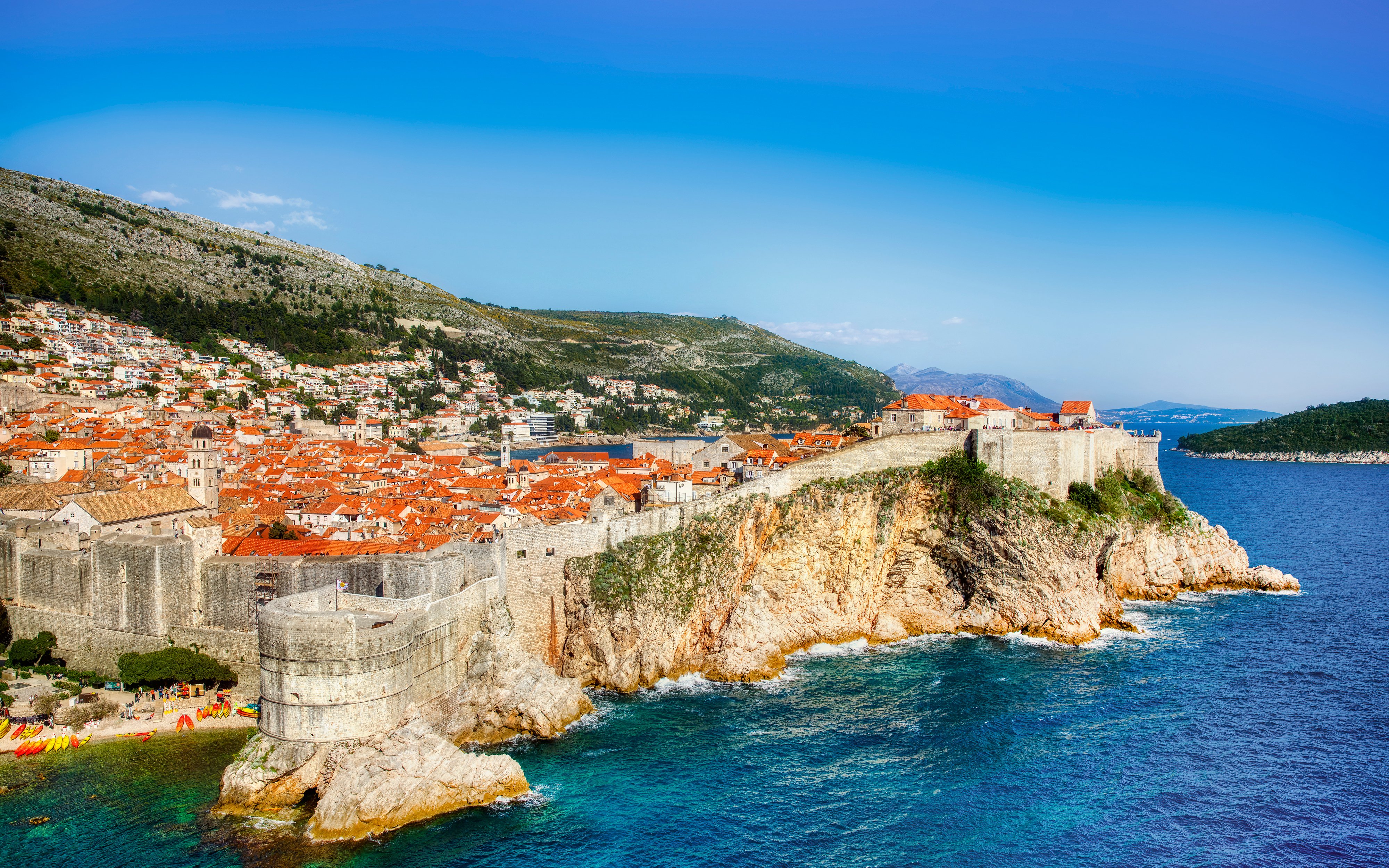 Old City walls and coastline of Dubrovnik, Croatia, with terracotta rooftops and Adriatic Sea.