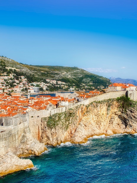 Old City walls and coastline of Dubrovnik, Croatia, with terracotta rooftops and Adriatic Sea.