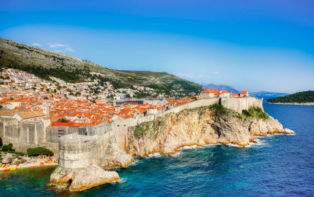 Old City walls and coastline of Dubrovnik, Croatia, with terracotta rooftops and Adriatic Sea.