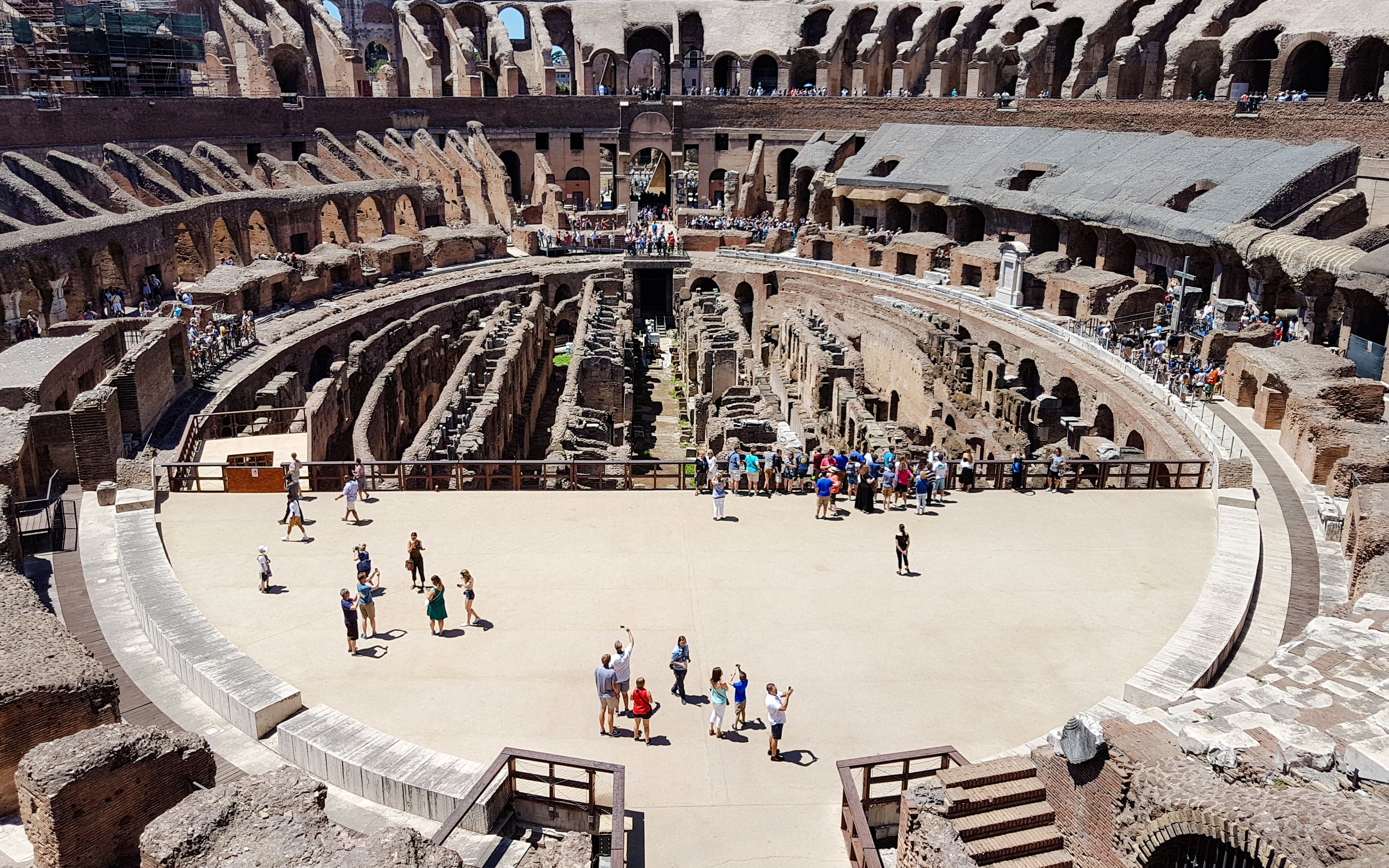 Tourists exploring the arena floor of the Colosseum in Rome.