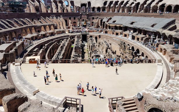 Tourists exploring the arena floor of the Colosseum in Rome.