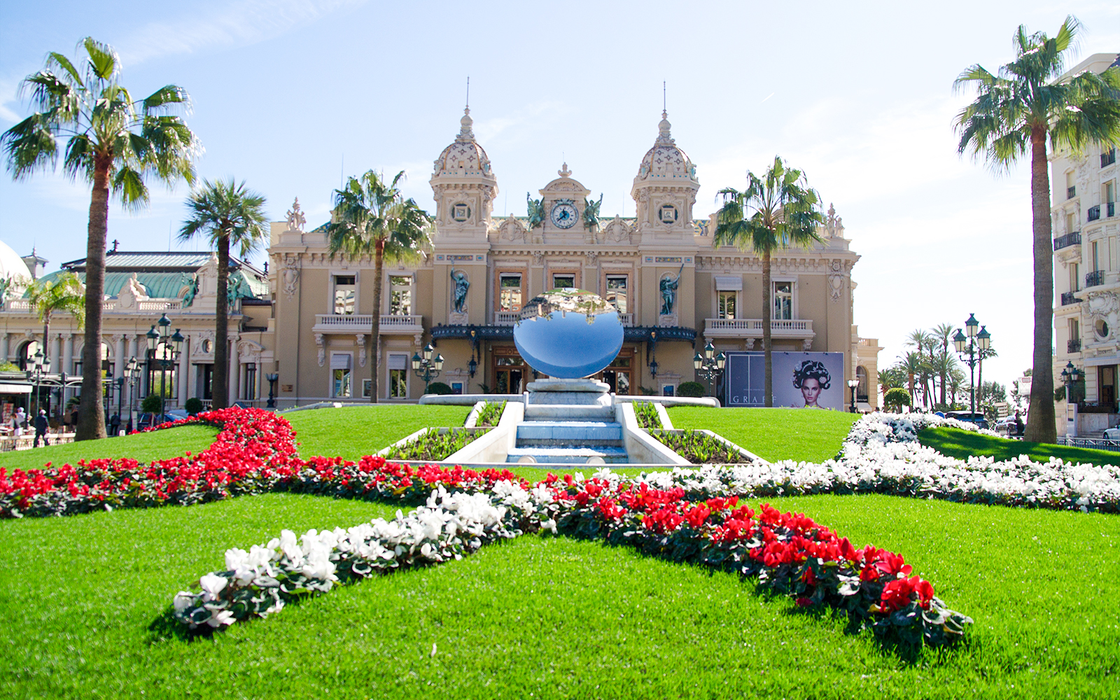 Monte Carlo Casino with gardens and reflective sculpture in front.