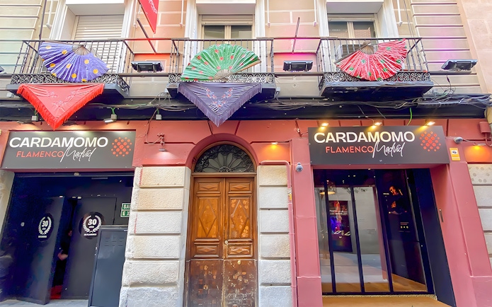 Facade of Cardamomo Flamenco venue in Madrid with colorful fans on balcony.