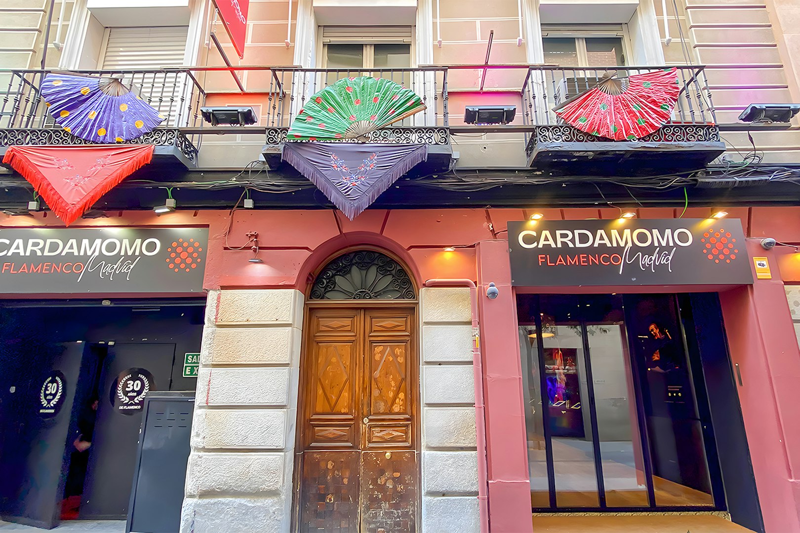 Facade of Cardamomo Flamenco venue in Madrid with colorful fans on balcony.