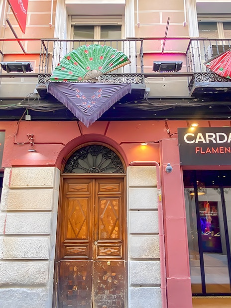 Facade of Cardamomo Flamenco venue in Madrid with colorful fans on balcony.