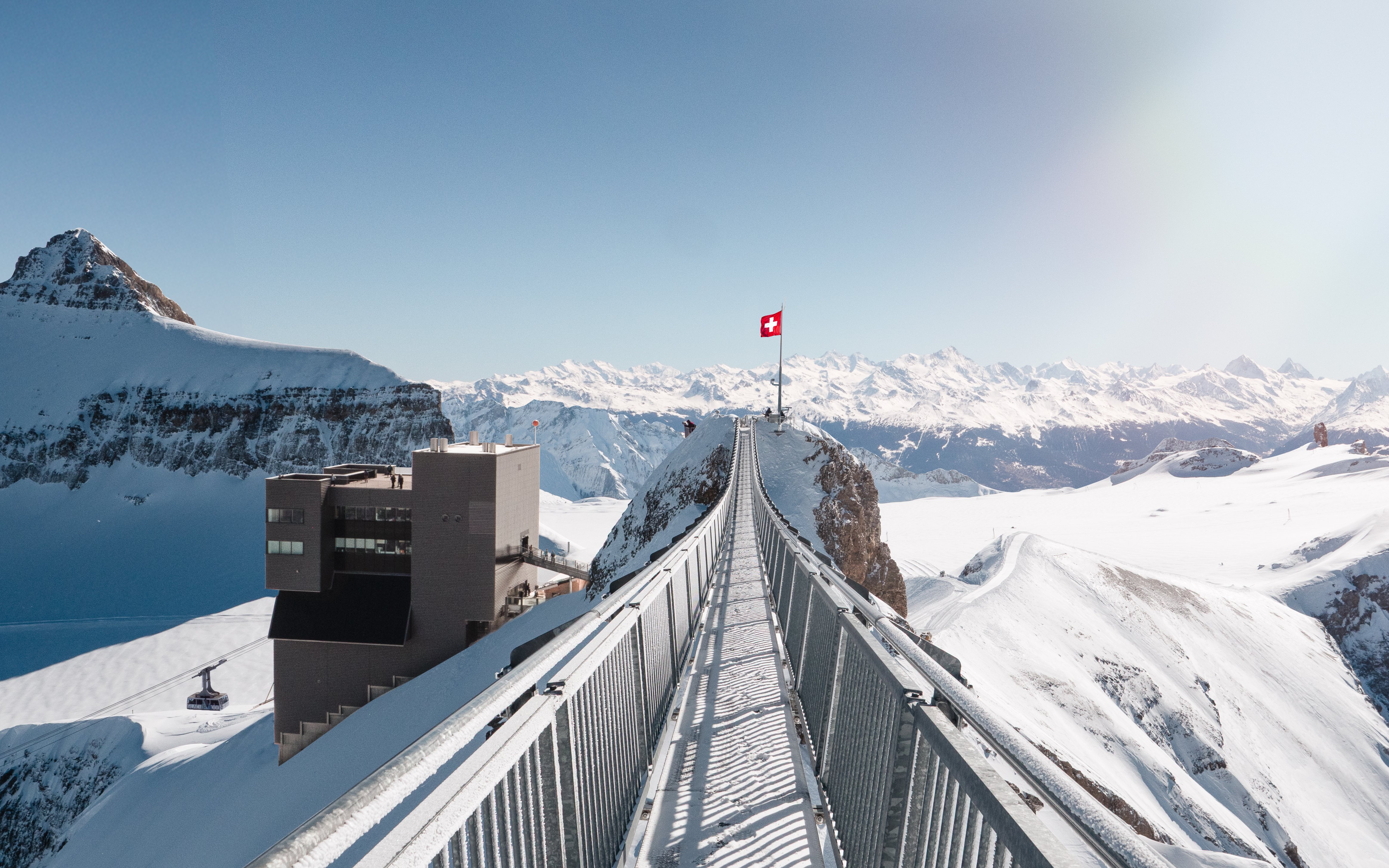 Suspension bridge at Glacier 3000 in Switzerland with snowy mountain views.