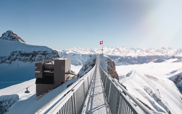 Suspension bridge at Glacier 3000 in Switzerland with snowy mountain views.