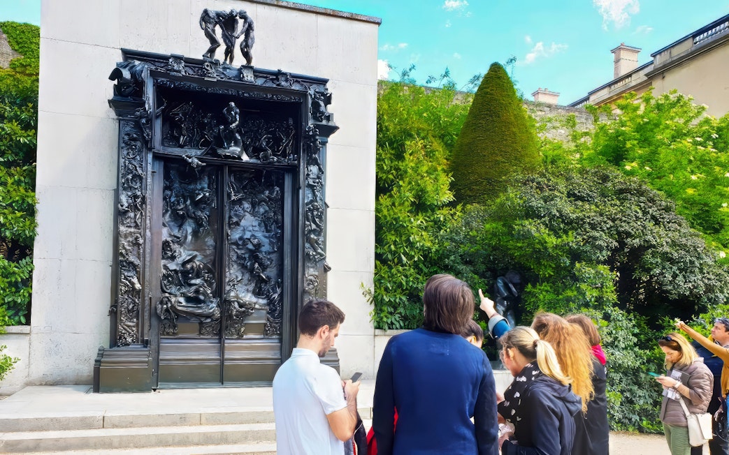 Visitors observing The Gates of Hell sculpture at Rodin Museum, Paris.