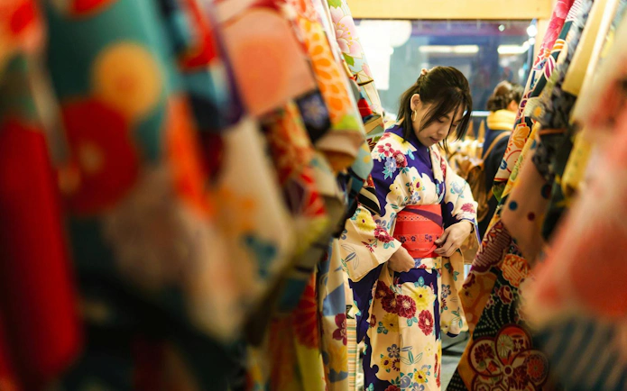Young woman in kimono rental shop in Japan adjusting floral kimono.