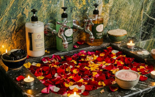 Traditional Moroccan hammam with rose petals, candles, and artisanal spa products.