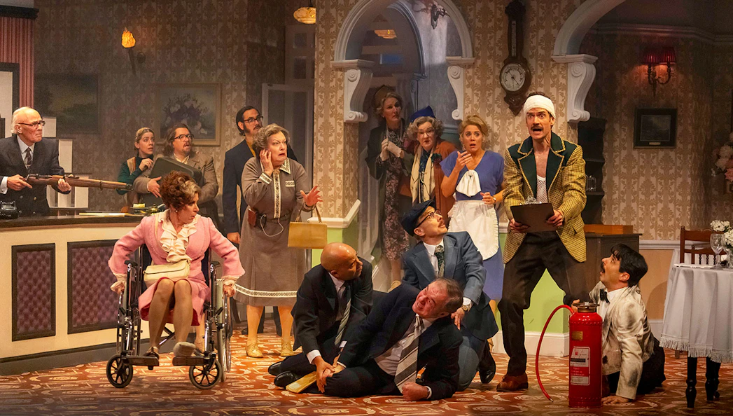 Theatrical scene depicting chaos in a hotel lobby, inspired by Fawlty Towers.