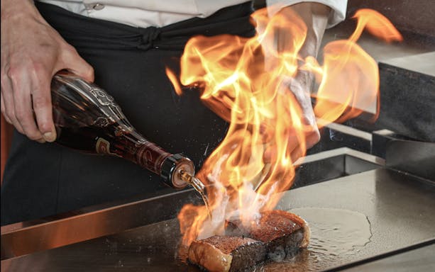 Chef flambéing A5 Kobe beef at Kobe Steak & Cafe Nobleurs.