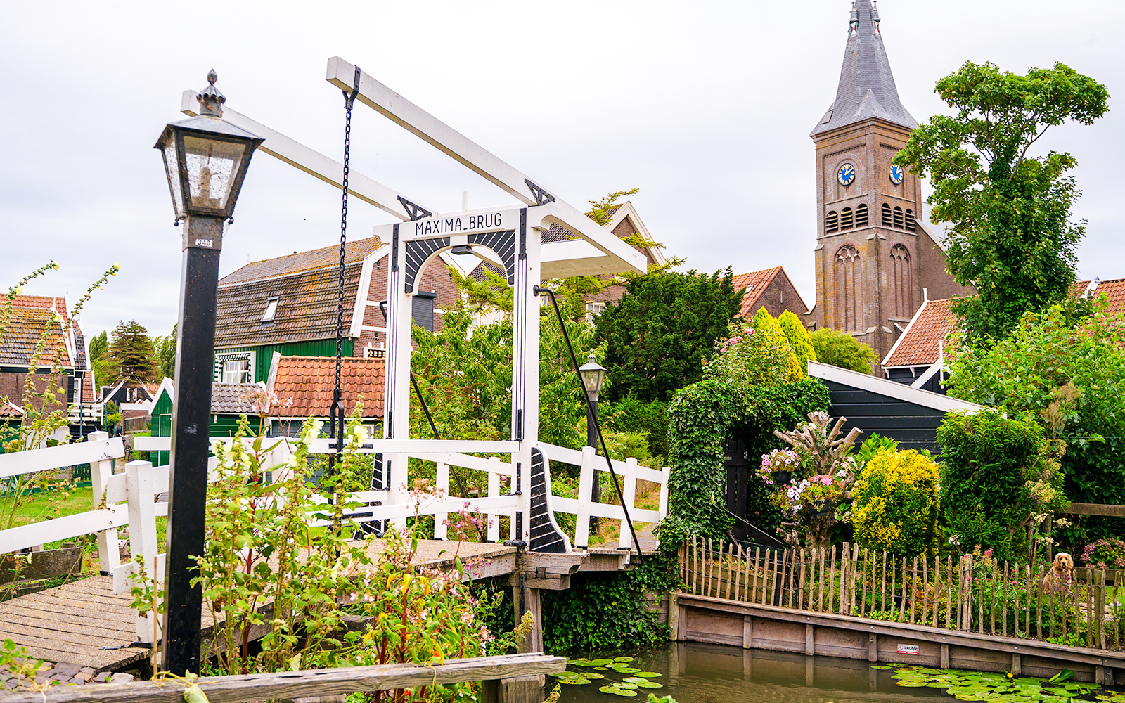 Maxima Bridge in Marken, Netherlands, with church tower and traditional houses in the background.