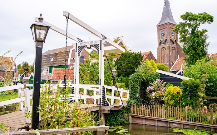 Maxima Bridge in Marken, Netherlands, with church tower and traditional houses in the background.