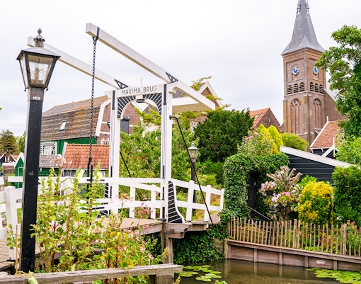Maxima Bridge in Marken, Netherlands, with church tower and traditional houses in the background.