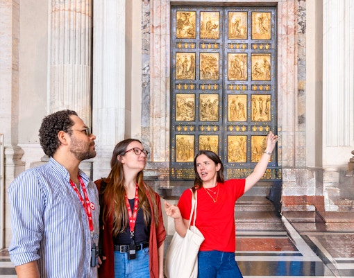 St. Peter's Basilica interior with visitors on a guided tour in Vatican City, Rome.
