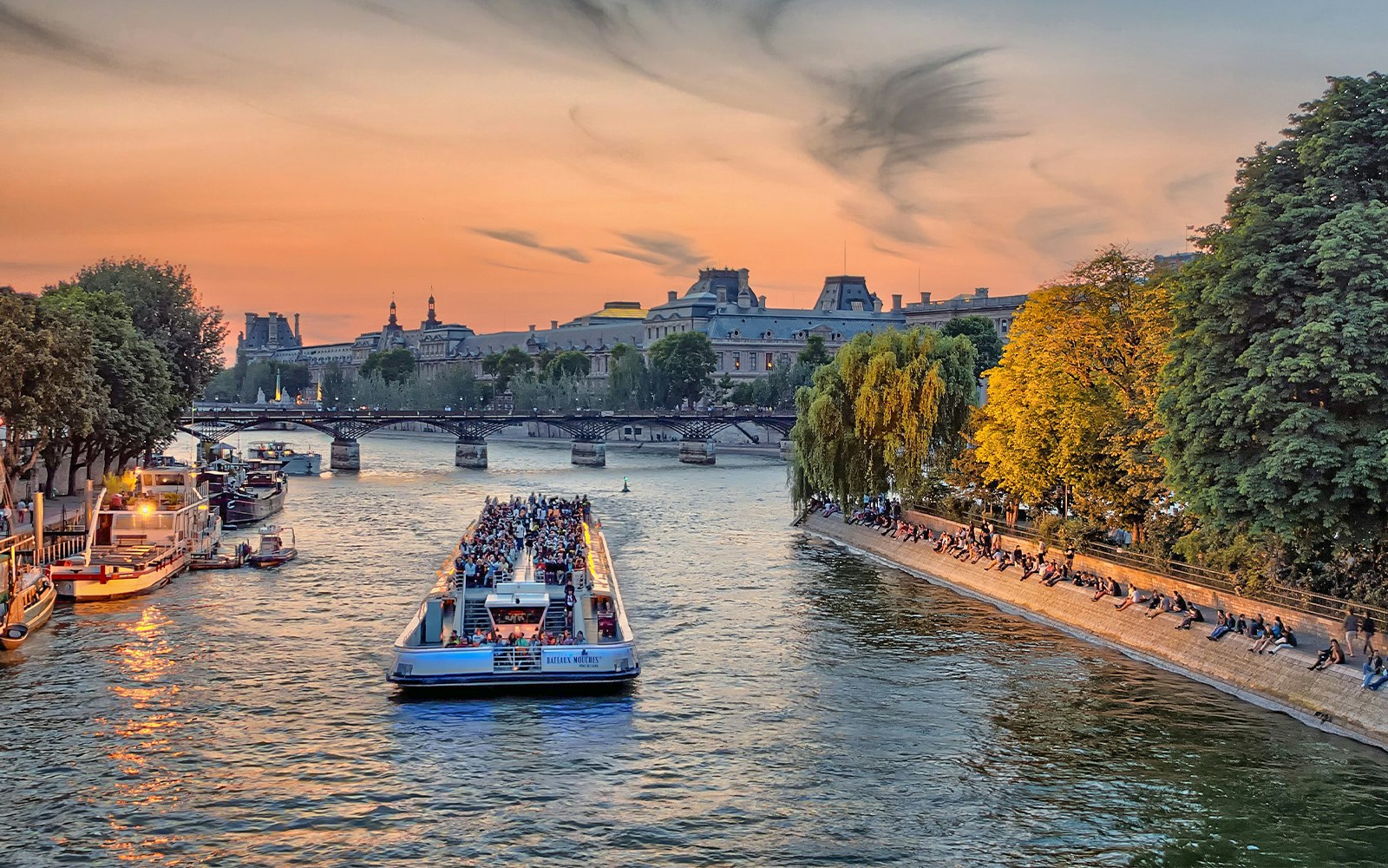 Seine River cruise in Paris with passengers enjoying a French breakfast on a sunny morning.