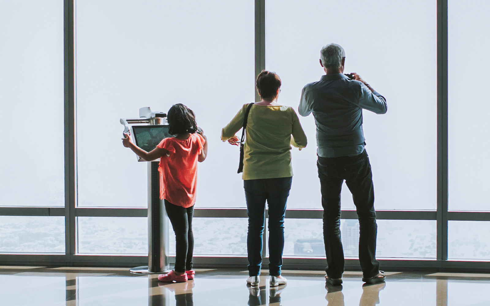 Family viewing London skyline from The Shard through digital telescope
