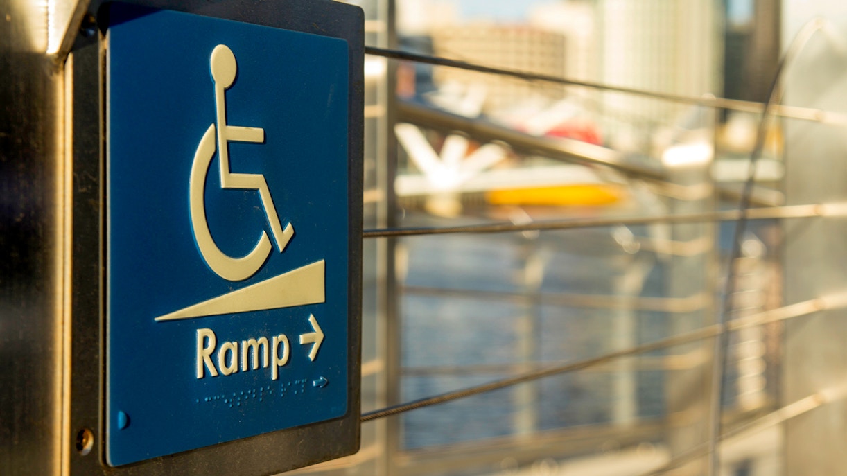 Wheelchair access ramp sign with cityscape background.