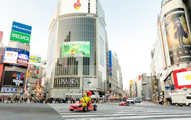 Tourists driving go karts on Shibuya streets during Tokyo go karting experience.
