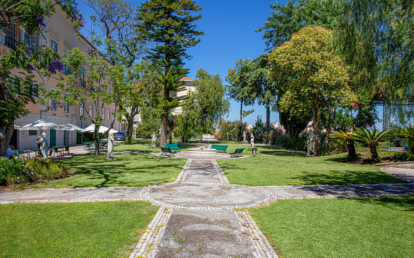 Garden view at the National Museum of Ancient Art, Lisbon, with statues and greenery.