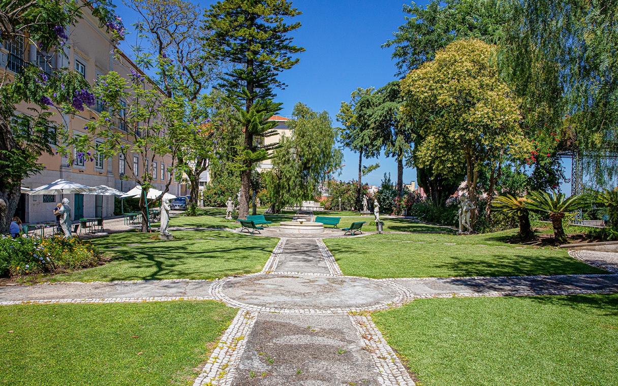 Garden view at the National Museum of Ancient Art, Lisbon, with statues and greenery.