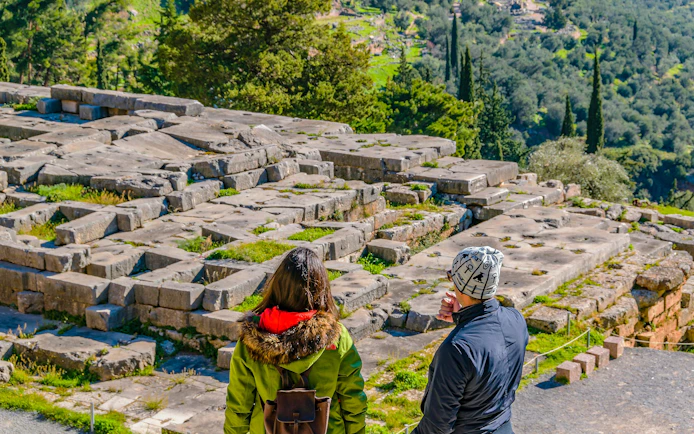 Visitors exploring ancient ruins at Delphi Sanctuary, Phocis, Greece.