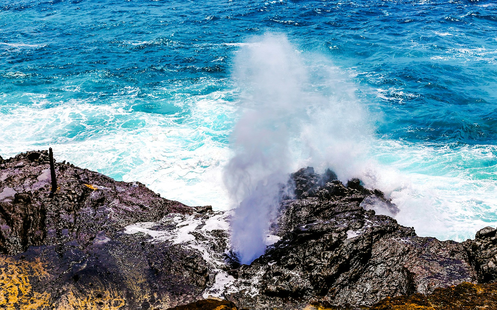Halona Blow Hole in Oahu, Hawaii, with ocean waves crashing against rocky shore.