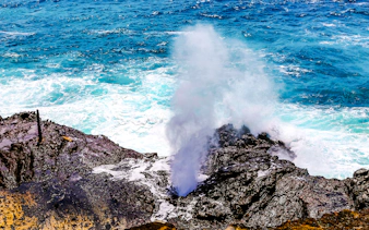 Halona Blow Hole in Oahu, Hawaii, with ocean waves crashing against rocky shore.