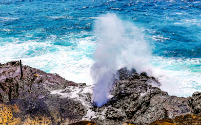 Halona Blow Hole in Oahu, Hawaii, with ocean waves crashing against rocky shore.