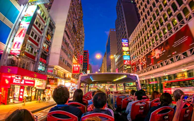 Open-top bus tour through vibrant Hong Kong streets at night.