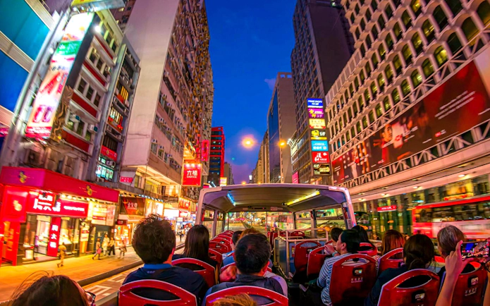 Open-top bus tour through vibrant Hong Kong streets at night.