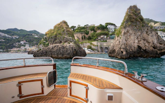 Cruise boat approaching rocky cliffs along the Amalfi Coast, Italy.
