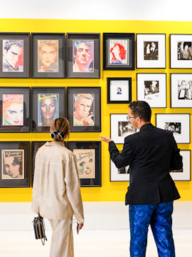 Visitors viewing Andy Warhol magazine covers at an exhibition.