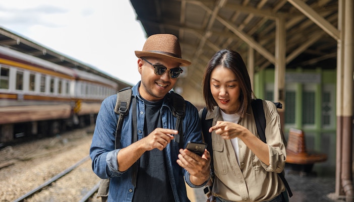 asian couple in europe checking train tickets in native language