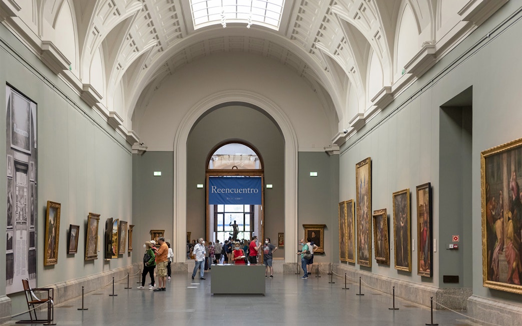 Tourists viewing art inside Prado Museum, Madrid day tour.