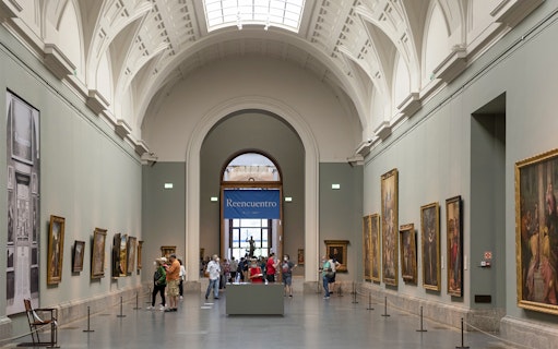 Tourists viewing art inside Prado Museum, Madrid day tour.