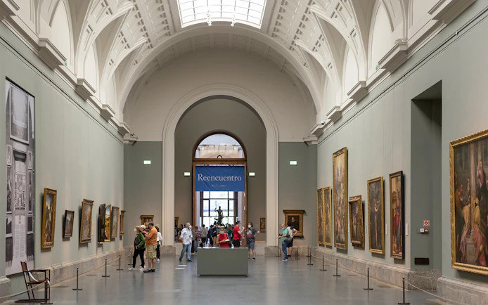 Tourists viewing art inside Prado Museum, Madrid day tour.