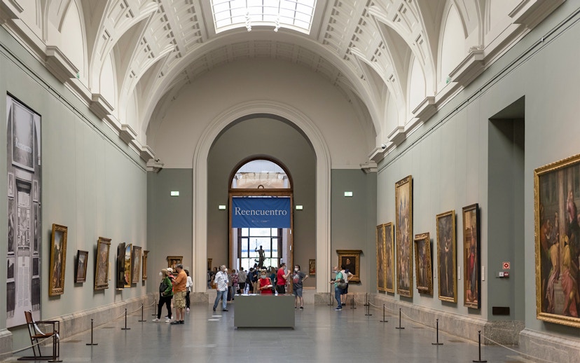 Tourists viewing art inside Prado Museum, Madrid day tour.