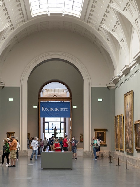 Tourists viewing art inside Prado Museum, Madrid day tour.