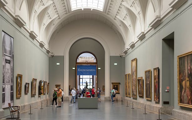 Tourists viewing art inside Prado Museum, Madrid day tour.
