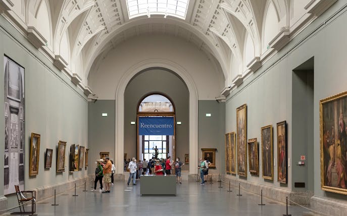 Tourists viewing art inside Prado Museum, Madrid day tour.