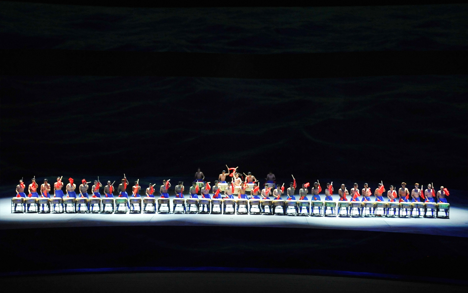 Performers on a multi-lifting platform in a synchronized drumming show.